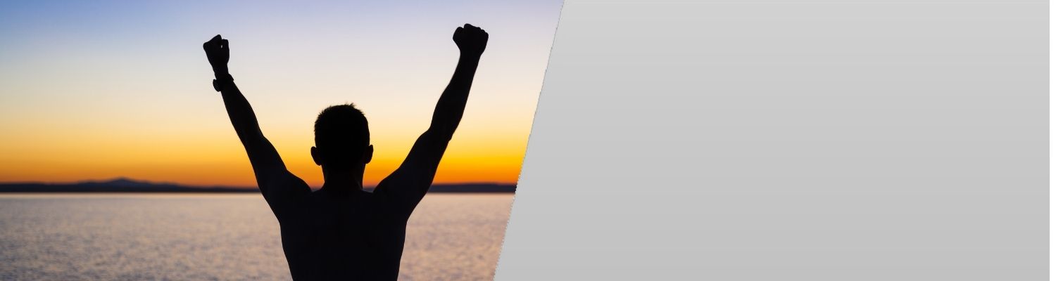 Stress free man stretching upwards on the beach during sunset